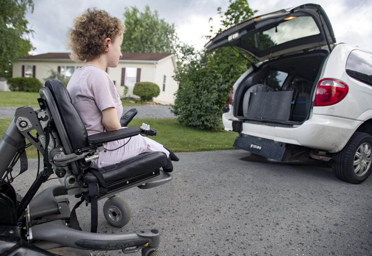 Dale Dyke waits for her mom to lower the ramp of their wheelchair accessible van outside of their Milesburg home on Tuesday, July 17, 2018.
