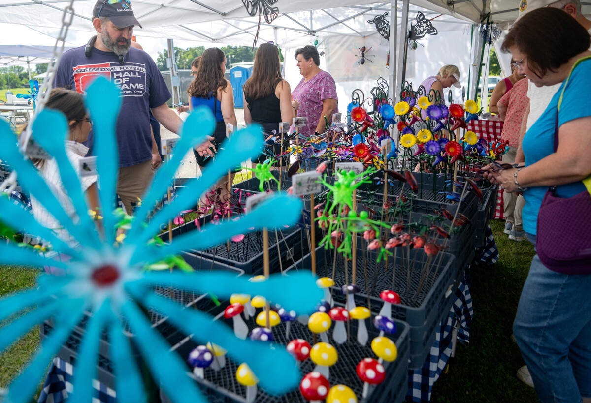 Customers browses the Metal Illusions booth at the People’s Choice Festival on Friday, July 14, 2023. All the creations are made from recycled metals and are powder coated to last outside.