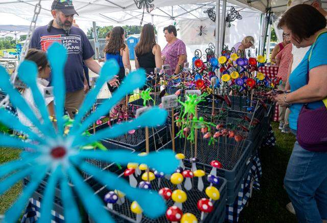 Customers browses the Metal Illusions booth at the People’s Choice Festival on Friday, July 14, 2023. All the creations are made from recycled metals and are powder coated to last outside.