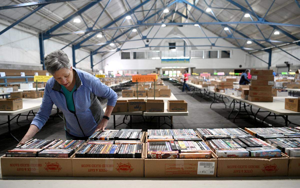 Mary Ann Blair organizes boxes of DVDs before the 2023 AAUW State College Used Book Sale at the Penn State Snider Agriculture Arena.