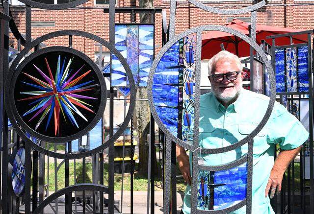 Roger Mathews of Mathews Gallery frames himself in his stained and beveled glass panels at the 57th Central Pennsylvania Festival of the Arts.