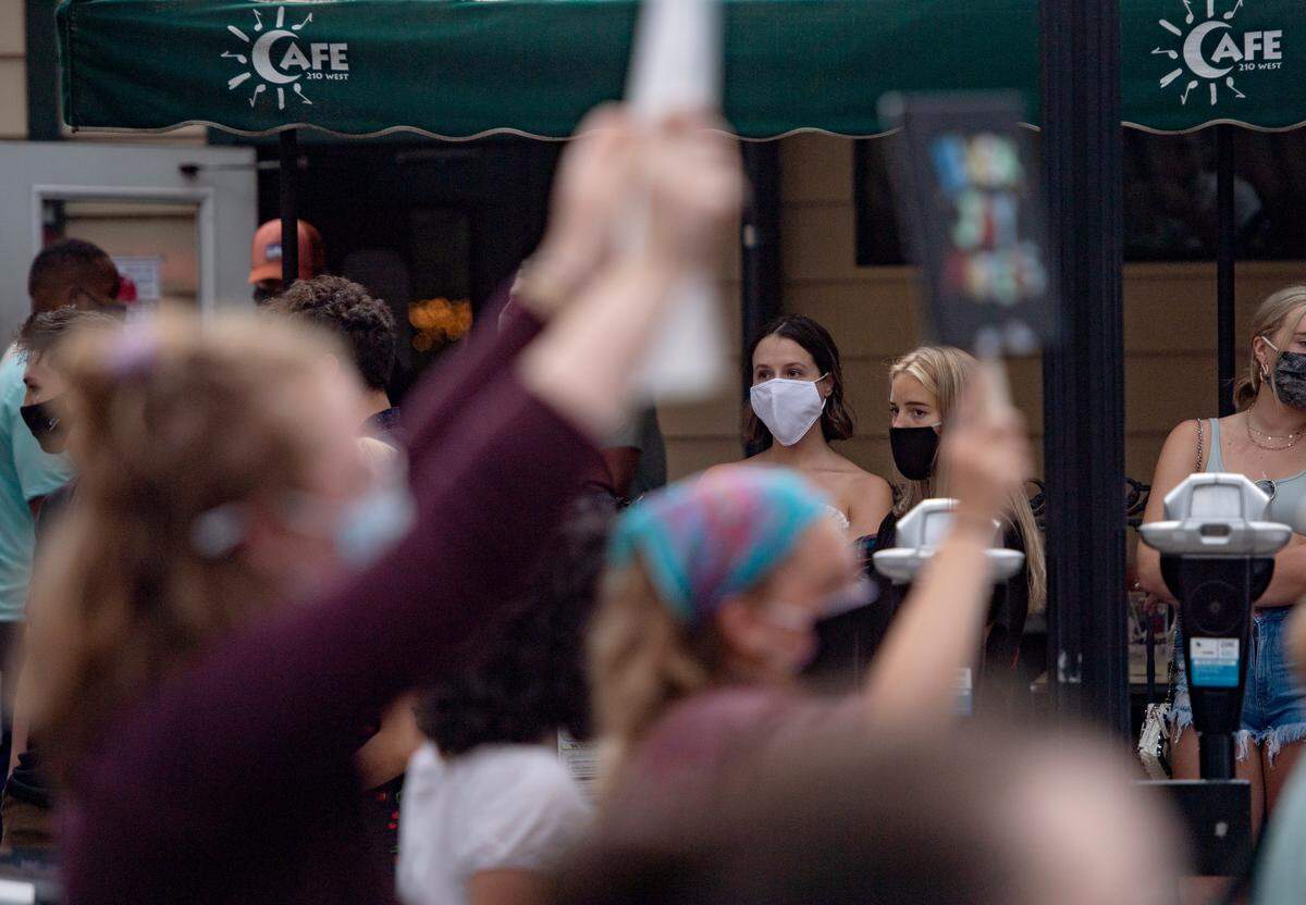 Patrons waiting in line for Cafe 210 West watch as a Black Lives Matter march walks down College Avenue on Saturday, Aug. 29, 2020.
