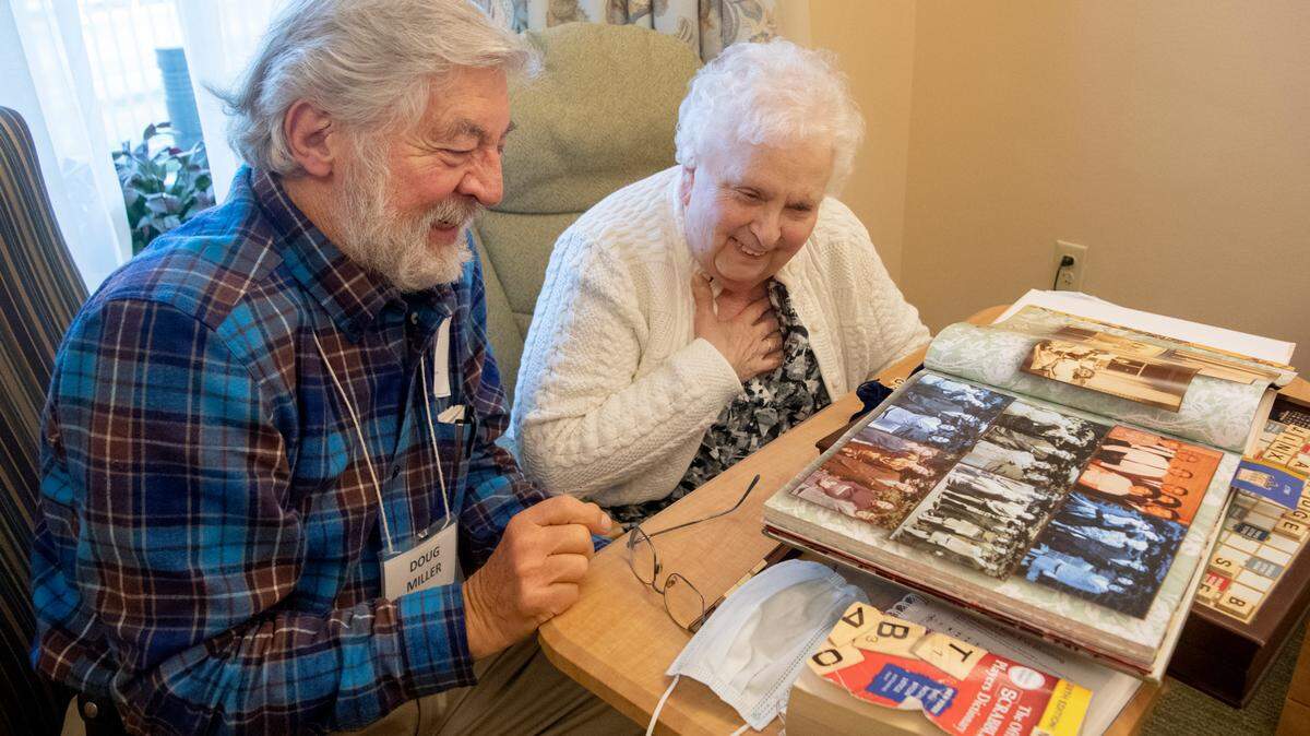 Doug Miller and his wife Grace laugh as they reminisce over photos of Grace’s family growing up while in her room at Foxdale Village on Thursday, Dec. 16, 2021.