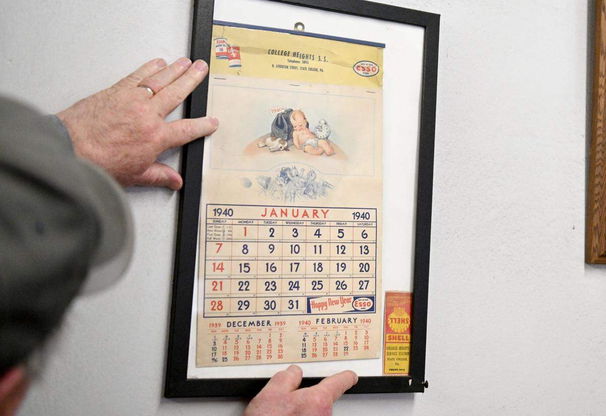 Gary Green adjusts a framed calendar page from 1940 that features the original College Heights Service Station name and a pack of matches from when the service station used Shell.