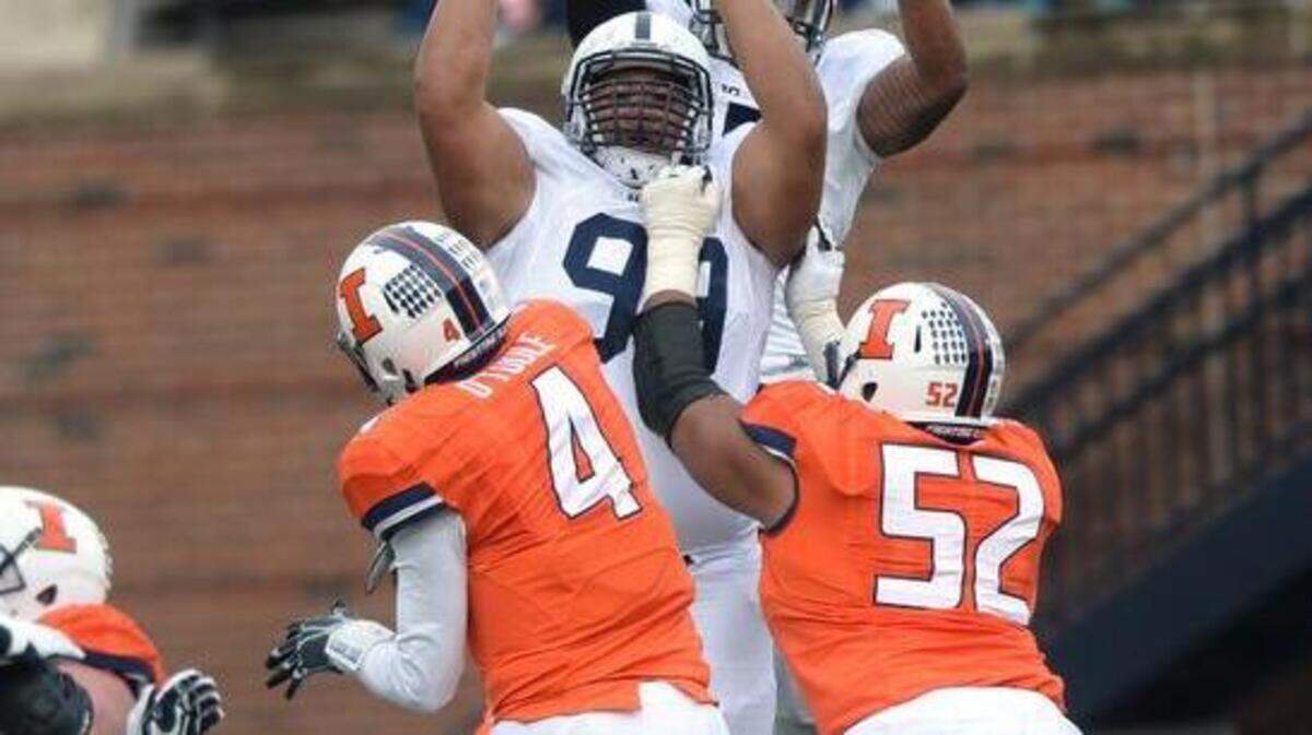Illinois’ Reilly O’Toole (4) throws around Penn State defenders during the Fighting Illini’s 16-14 win over the Nittany Lions on Saturday.
