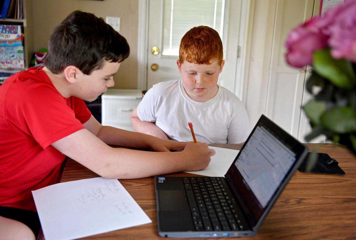Penns Valley sixth grader Luke Ruoff helps his younger brother Gavin Hettinger work through a math problem as they do their school work from home on Thursday, May 14, 2020.