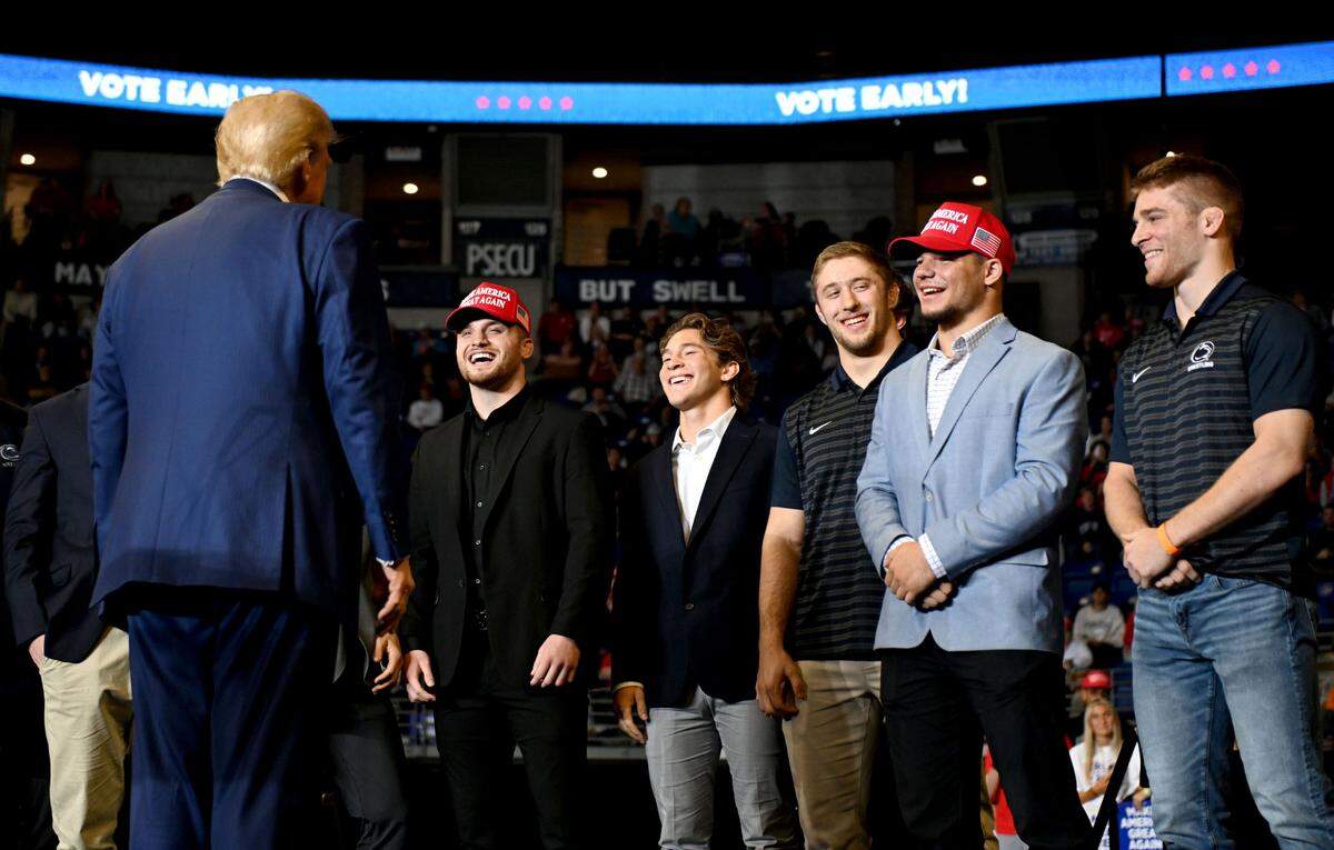 Donald Trump laughs with former and current Penn State wrestlers after welcoming them to the stage during his rally at the Bryce Jordan Center on Saturday, Oct. 26, 2024.