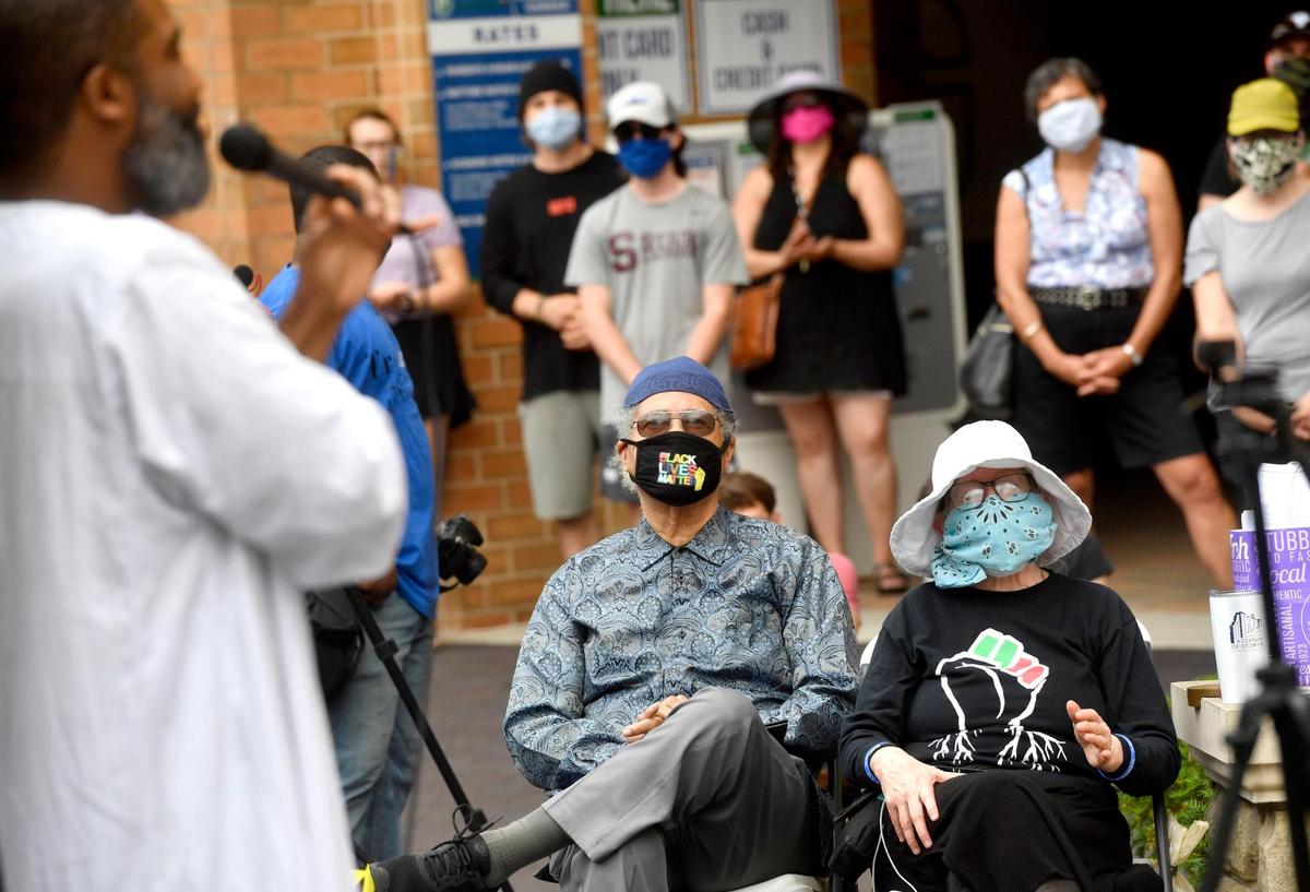 Wearing a face mask reading “Black Lives Matter,” Charles Dumas watches Eric Ian Farmer perform during the inaugural Juneteenth celebration hosted by the State College NAACP at MLK Plaza in State College on Friday, June 19, 2020.