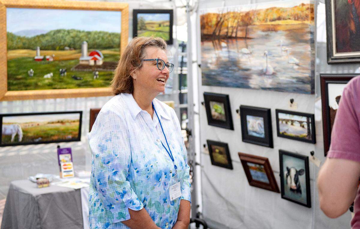 Paintings of animals surround Lina Ferrara as she chats with visitors to her booth during the Central Pennsylvania Festival of the Arts on Friday, July 11, 2025.