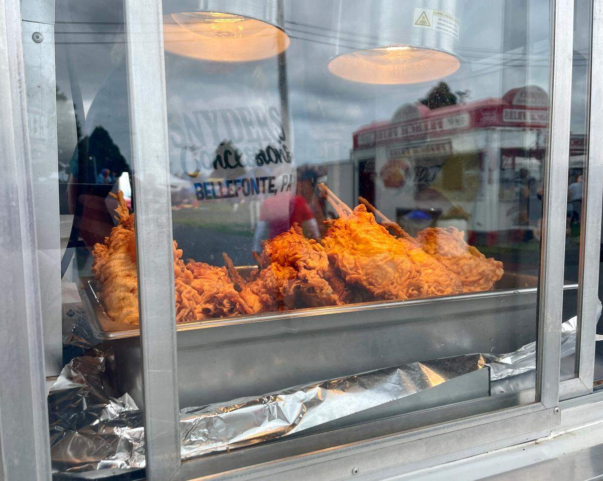 Skewered fried chicken breasts sit under a heat lamp at People’s Choice’s Chicken on a Stick stand.