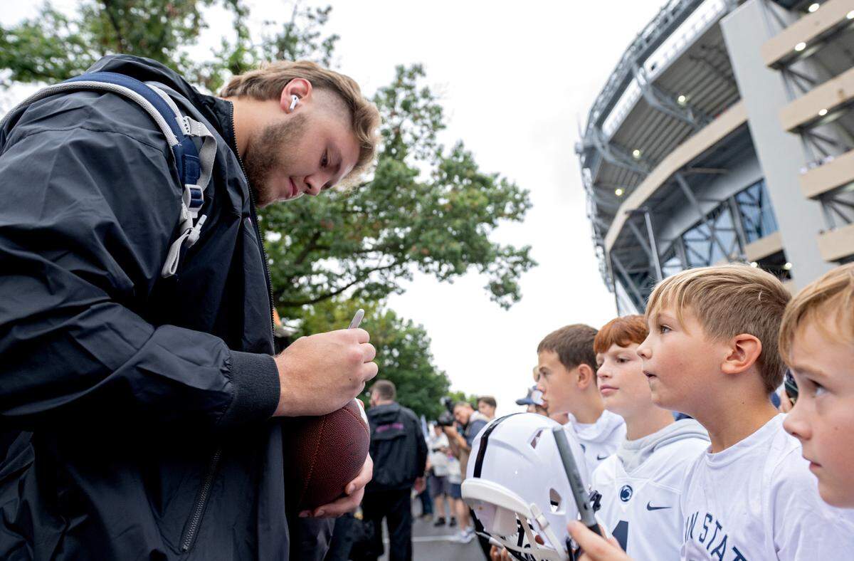 Penn State offensive lineman Nolan Rucci signs autographs for young fans as the team arrives at Beaver Stadium for the Homecoming game on Saturday, Sept. 28, 2024.