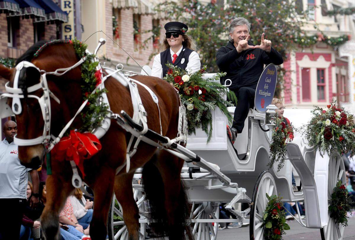 Utah football coach Kyle Whittingham holds up a “U” as he spots several players cheering him along on Main Street USA in Disneyland as part of the Rose Bowl kick off event on Wednesday, Dec. 28, 2022