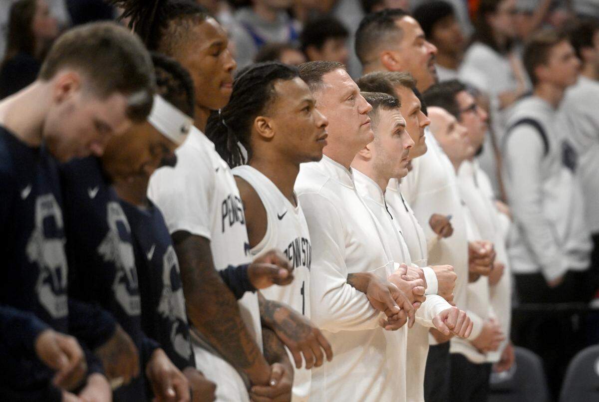 Penn State men’s basketball coach Mike Rhoades links arms with his player for the national anthem before the game on Monday, Nov. 6, 2023.