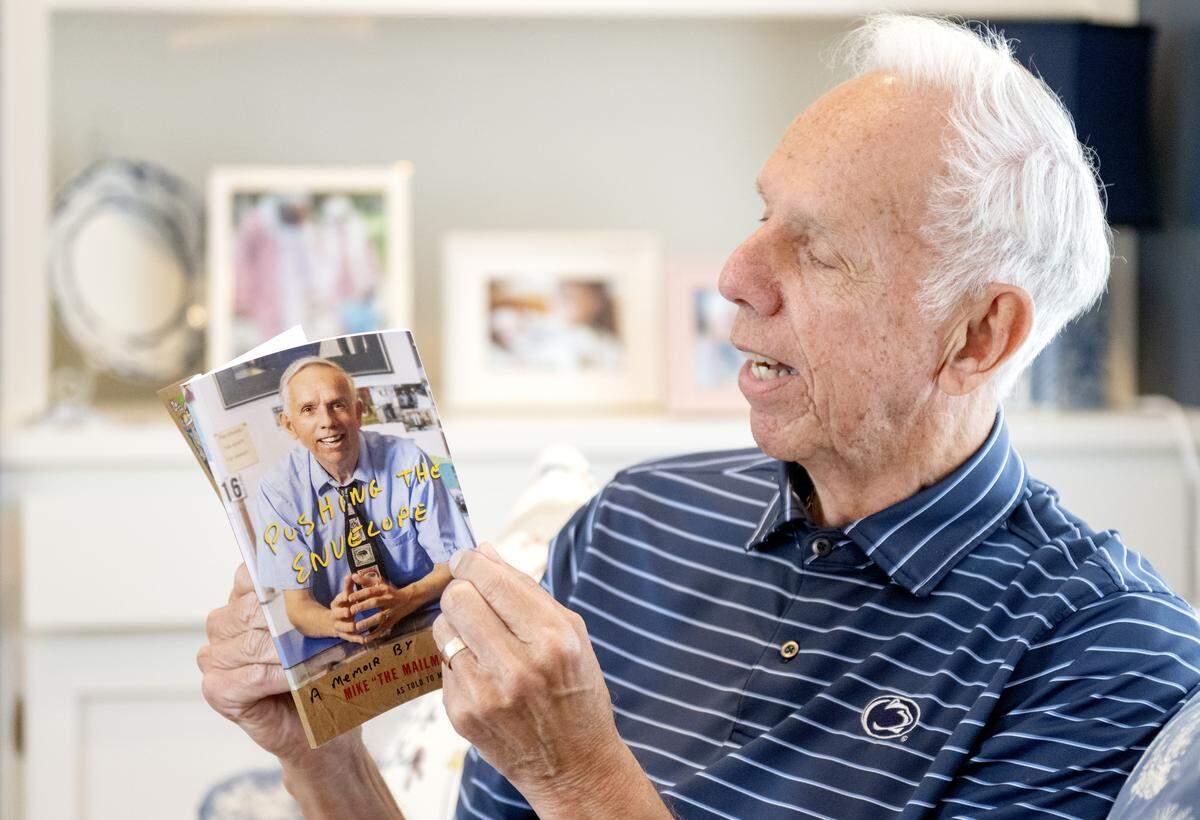 Mike Herr, known as Mike the Mailman, flips through his memoir “Pushing the Envelope” in his home on Tuesday, Oct. 21, 2025.  