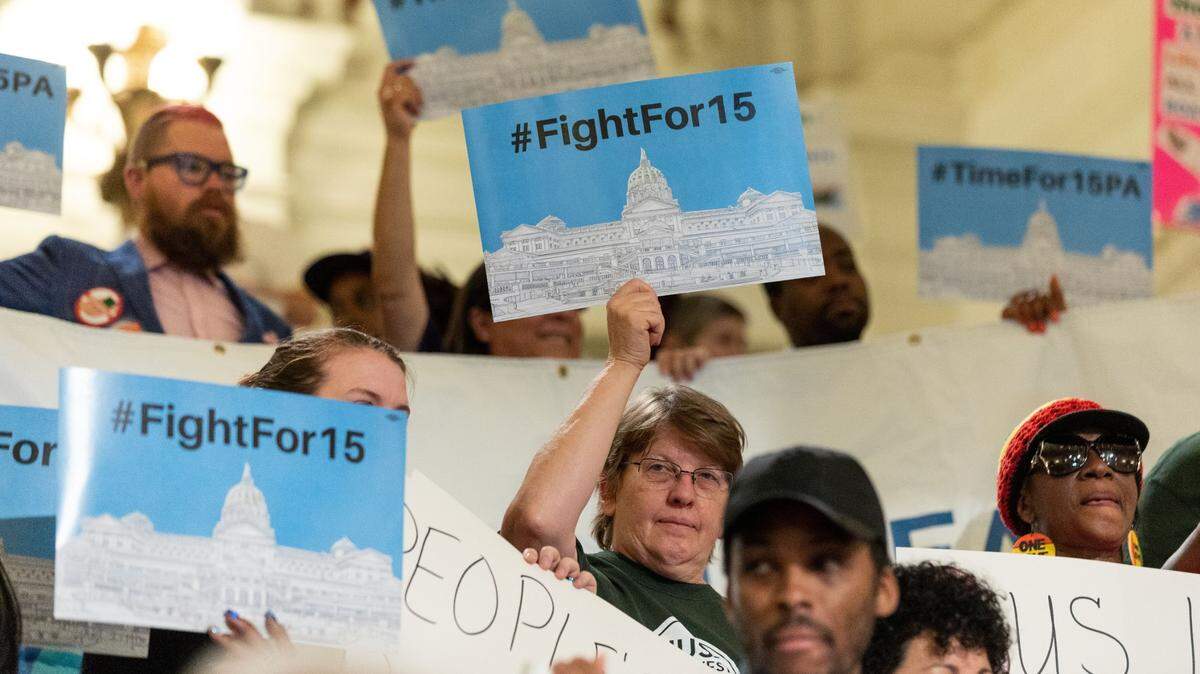 People hold up signs during a press conference and rally in 2019 calling for a $15 minimum wage.