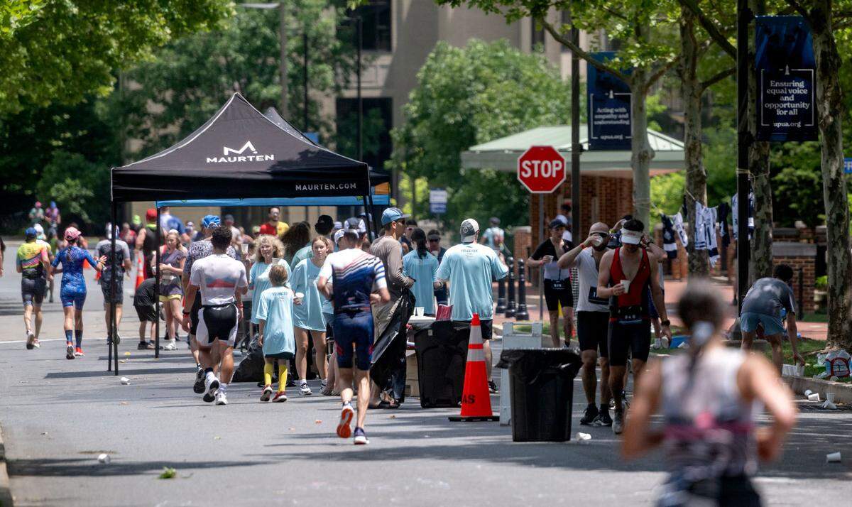 Volunteers hand out water to athletes during the 13.1 mile run in the Ironman 70.3 Pennsylvania Happy Valley on Sunday, June 30, 2024.