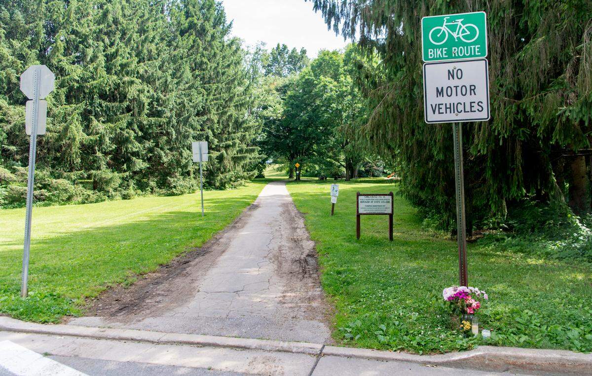 Flowers and a candle sit next to a sign for the bike path that crosses Edgewood Circle on Thursday, June 16, 2022.