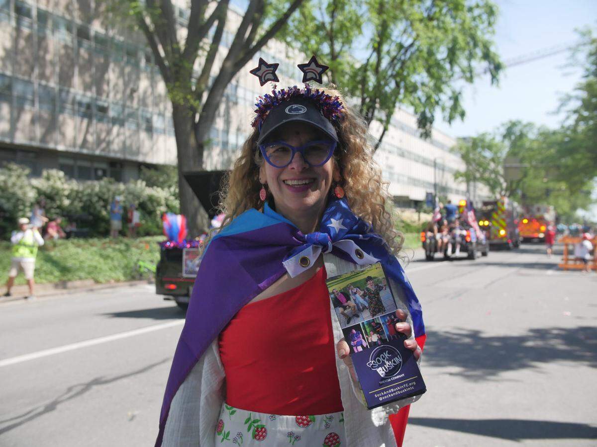 A woman with a Pride flag mixed with stars and stripes passed out Sock & Buskin Theatre Company pamphlets at the 4th Fest Parade.