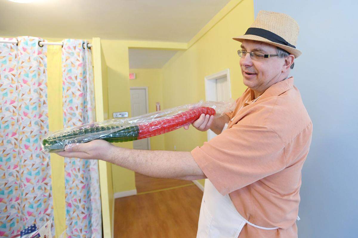 Pappy Chuck's Candy Shoppe owner Chuck Kormanski holds up a giant gummy worm on July 1 at his store in Bellefonte.