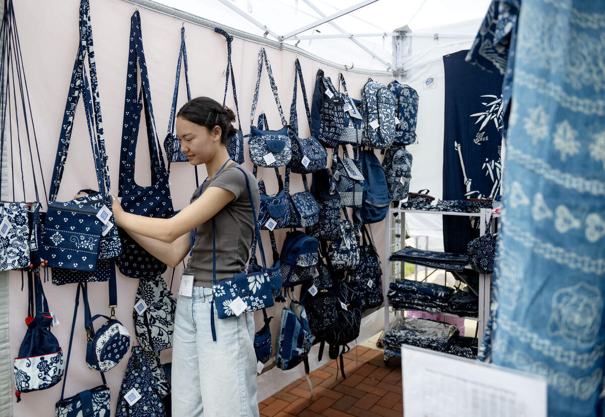 Phoenix Bernardin organizes some of the handmade fabric products by her and her mom at their booth True Blue Collections during the Central Pennsylvania Festival of the Arts on Friday, July 10, 2026.