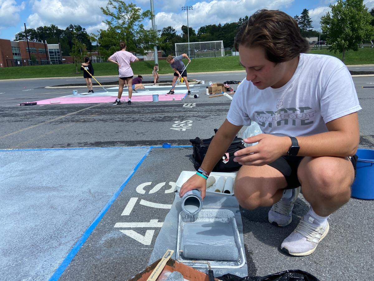 Senior Jacob Will laying down the base coat for his Mini Thon and Four Diamonds inspired parking space at State High on Wednesday, Aug. 18, 2023.