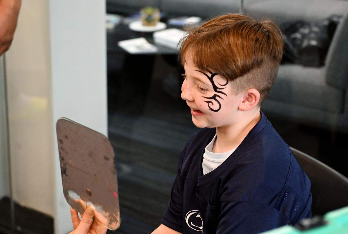 Christian Holder, 8, laughs as he sees the facepaint he got to look like Mike Tyson along with several football players during the Thon Explorers event at the Lasch Building on Saturday, Feb. 21, 2026.  