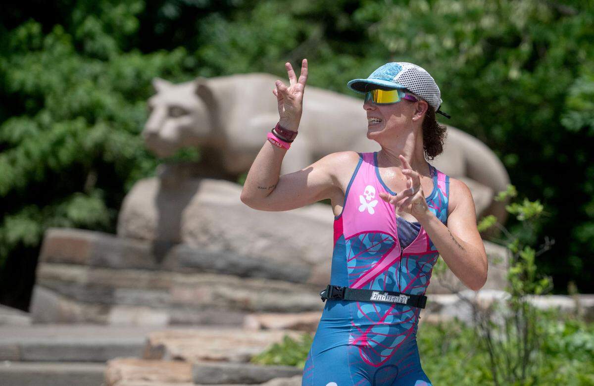 An athletes jokes as she runs past the Nittany Lion shrine during the Ironman 70.3 Pennsylvania Happy Valley on Sunday, June 30, 2024.
