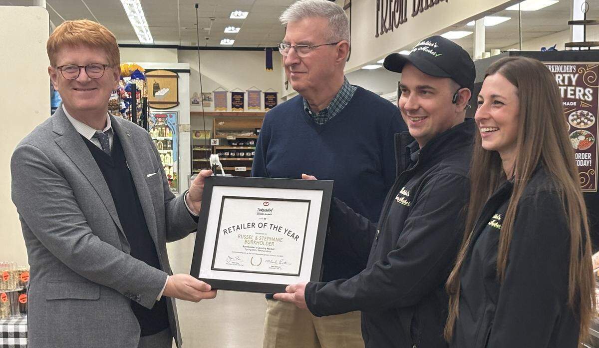 Burkholder’s Country Market co-owners Russ and Stephanie Burkholder, far right, receive a framed certificate as a 2026 Independent Grocers Alliance (IGA) USA Centennial Retailer of the Year from IGA President/CEO John Ross, far left, on March 5, 2026.