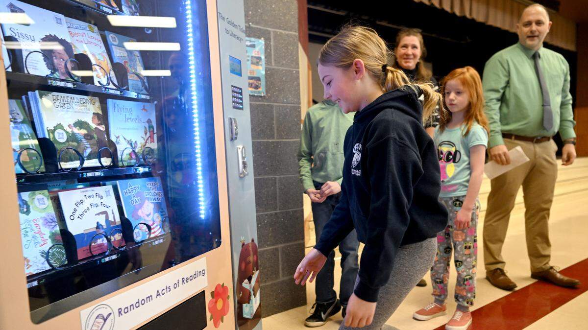 Kensley Praskovich gets a book from The Golden Ticket to Literacy book vending machine after it was was introduced at Centre Hall Elementary on Friday, Feb. 3, 2023.