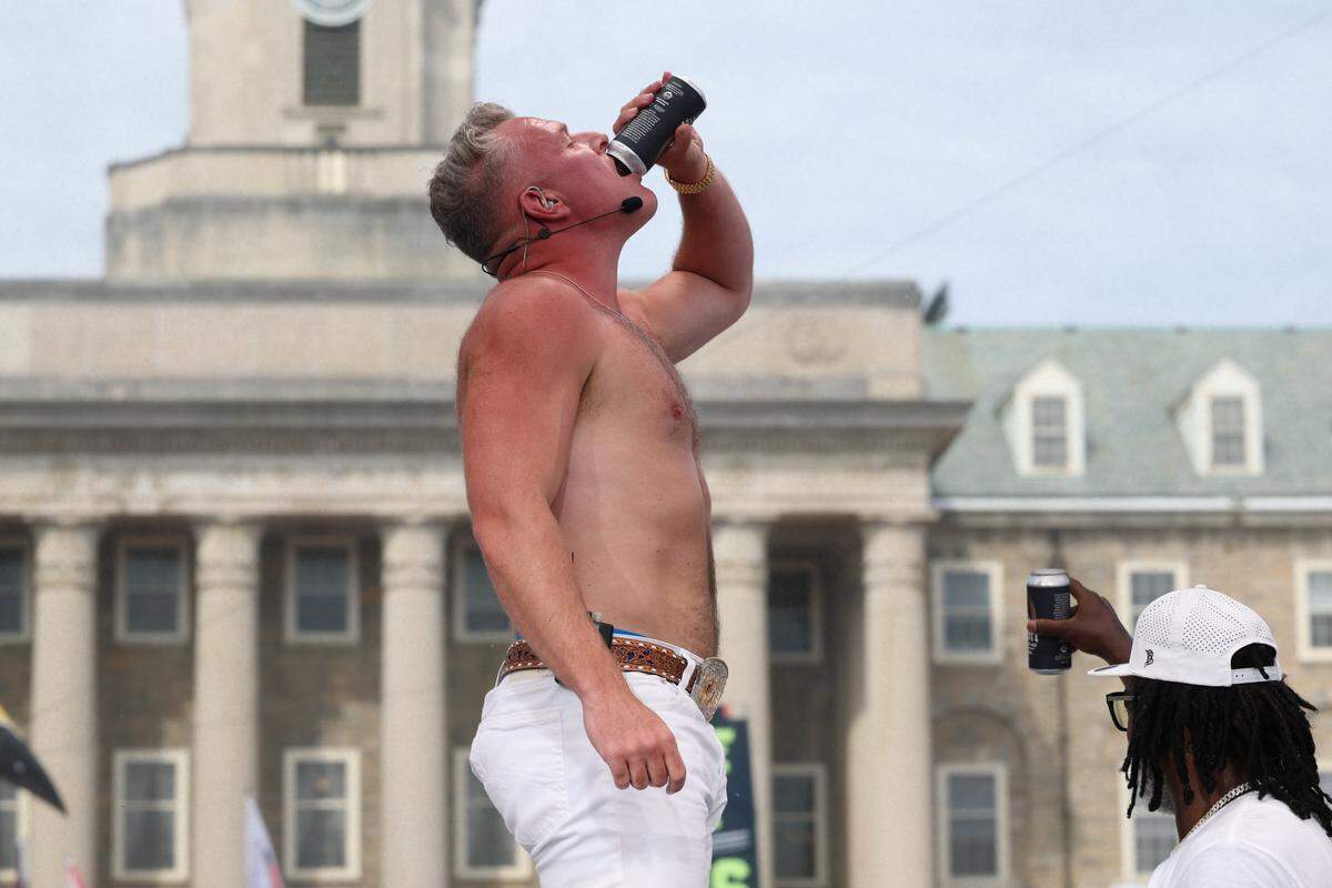 Pat McAfee cracks open a beverage after picking Penn State to beat Oregon, while PSU legend LaVar Arrington (right) looks to the crowd, during ESPN’s College GameDay on Saturday, Sept. 27, 2025, on the Old Main lawn at Penn State.