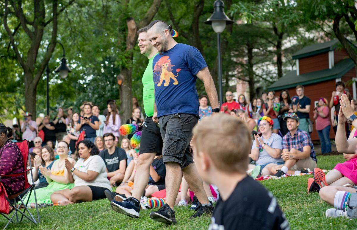 Travis Strube and Mike Bidoli smile as they walk through the crowd to be married at the State College Pride celebration on Saturday, June 11, 2022.