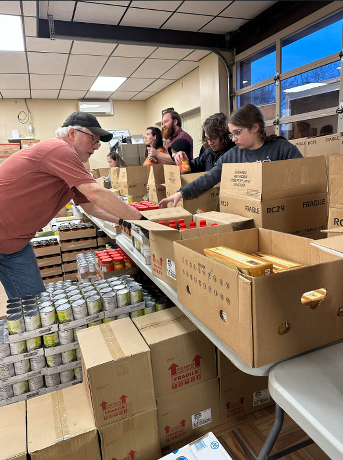 Volunteers pack food boxes at a packing session at CommonFood Centre County’s new packing center.