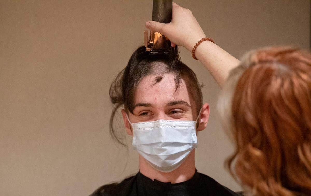 Luke Connolly looks to his friends as Whitney Maitre buzz cuts his hair Tuesday during the Penn State Thon “No Hair, Don’t Care” event.
