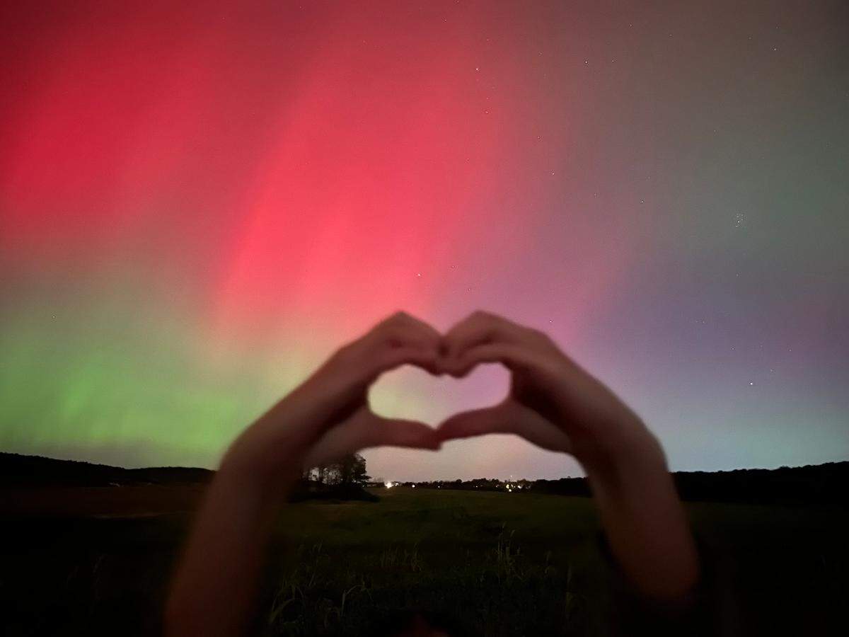 In a photo submitted by Jackie Elliott, her daughter Maeve makes heart hands in front of the northern lights as seen off of Houtz Lane in Port Matilda.