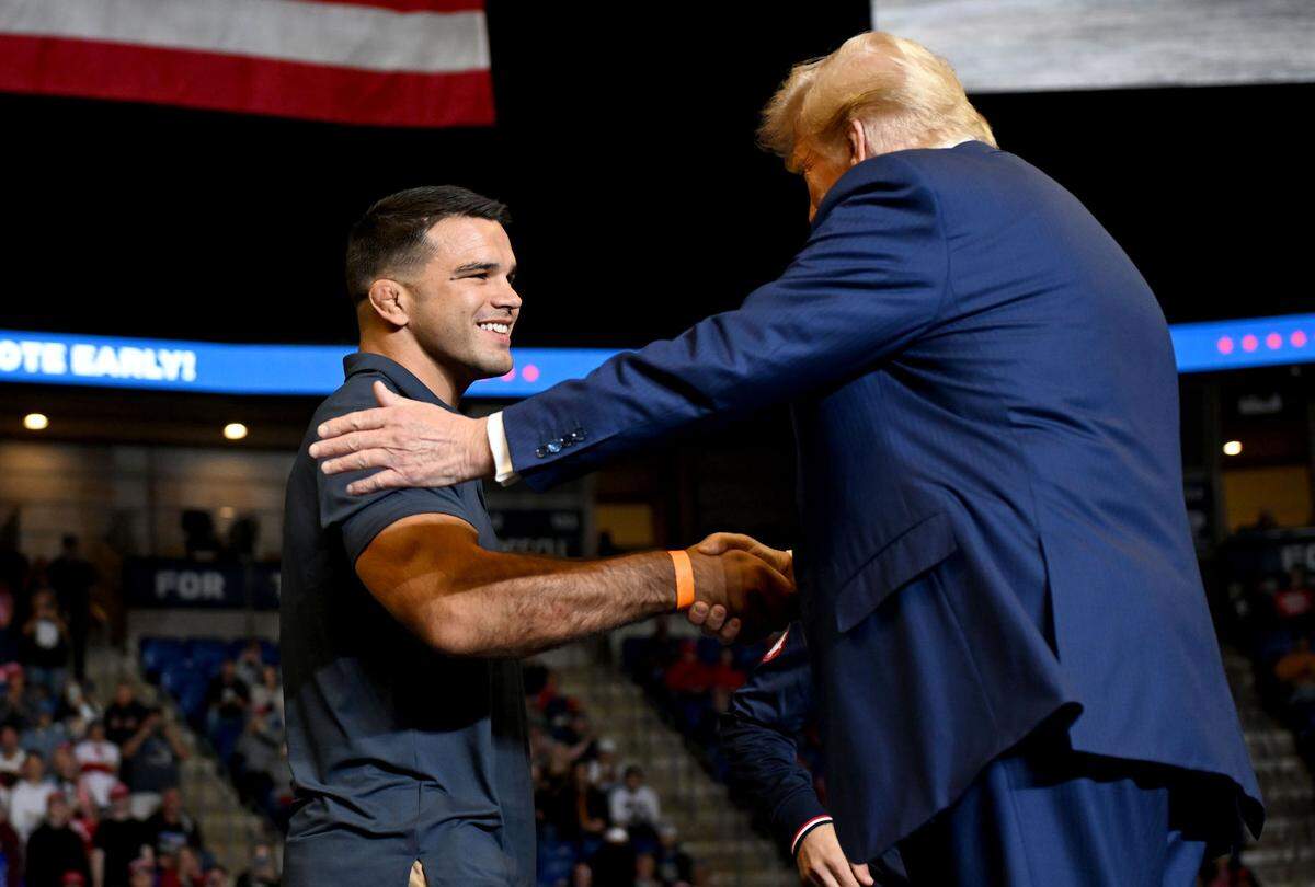 Donald Trump shakes hands with former and current Penn State wrestlers as he welcomes them to the stage during his rally at the Bryce Jordan Center on Saturday, Oct. 26, 2024.