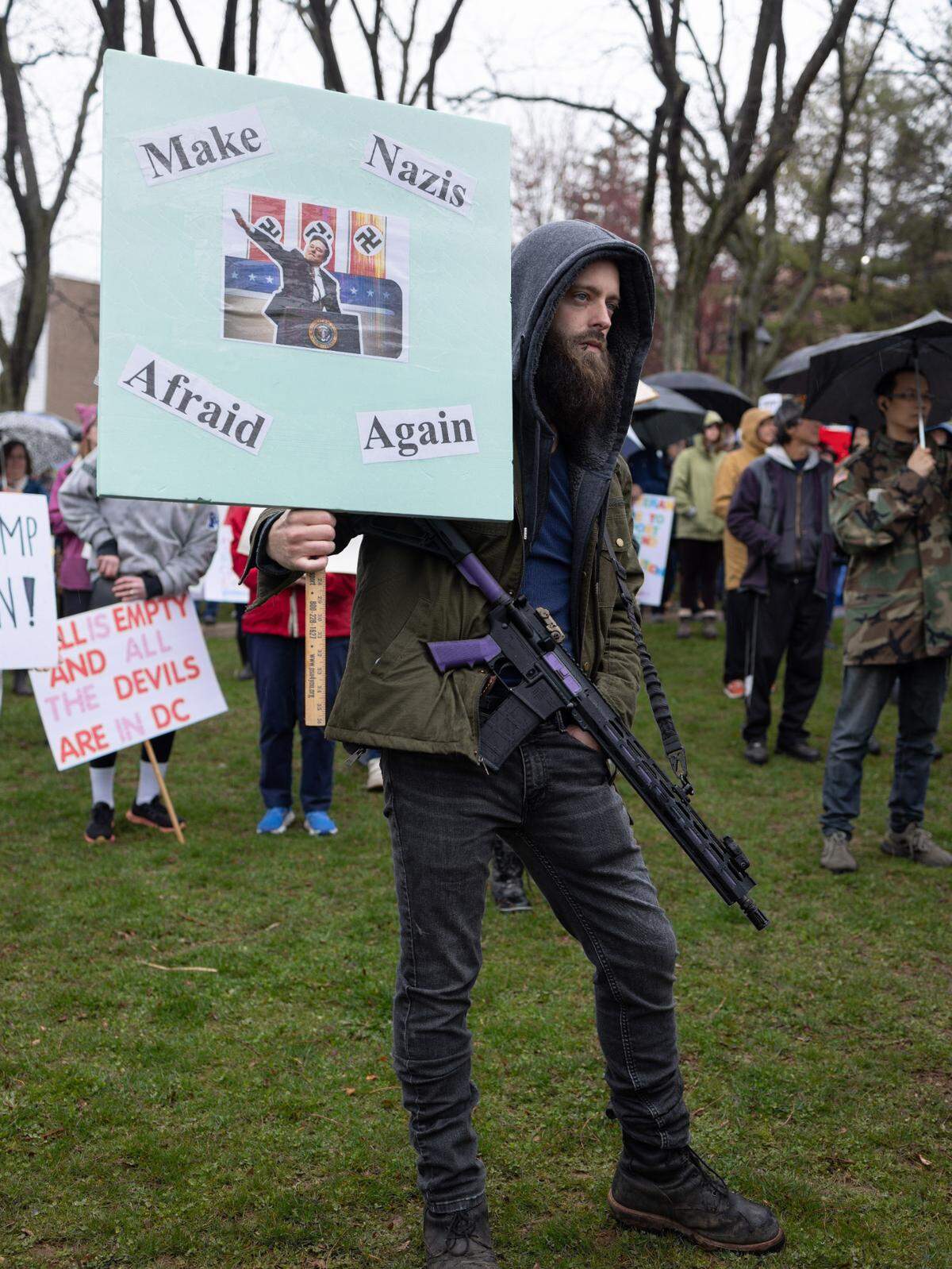Garrett Allison holds a sign in one hand while carrying a firearm — he’s a lawful conceal carry holder and, according to organizers, police said there were no red flags — during the “Hands Off!” rally at State College’s Sidney Friedman Park, in opposition of President Donald Trump. The event was held without incident and was part of a nationwide effort that saw more than 1,000 similar rallies held across all 50 states.