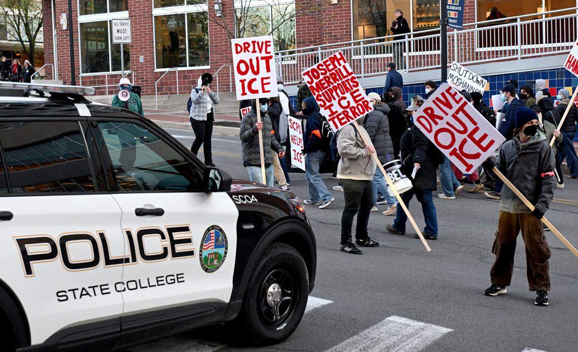 ICE protesters block a State College Police car from turning out of the Fraser Street garage as they march up the street on Monday, April 20, 2026.  