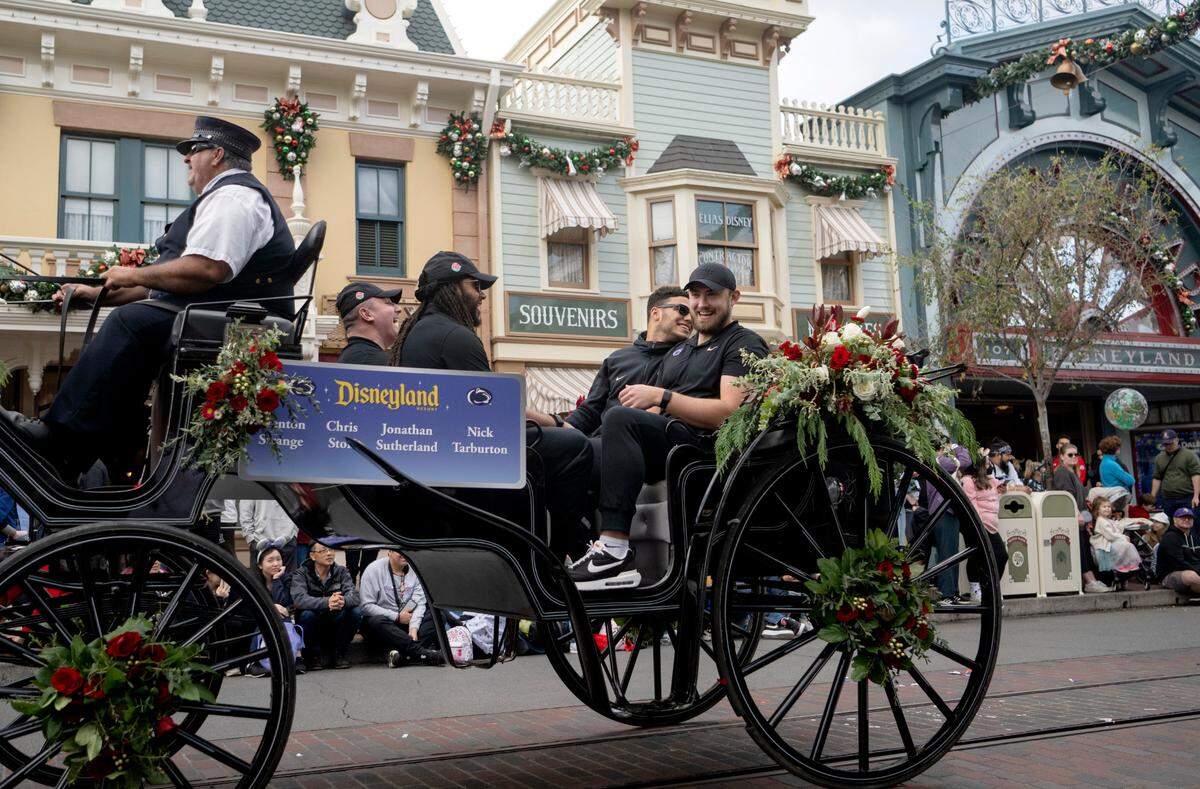 Penn State football players Nick Tarburton, Jonathan Sutherland, Brenton Strange and Chris Stoll ride in a carriage along Main Street USA in Disneyland as part of the Rose Bowl kick off event on Wednesday, Dec. 28, 2022
