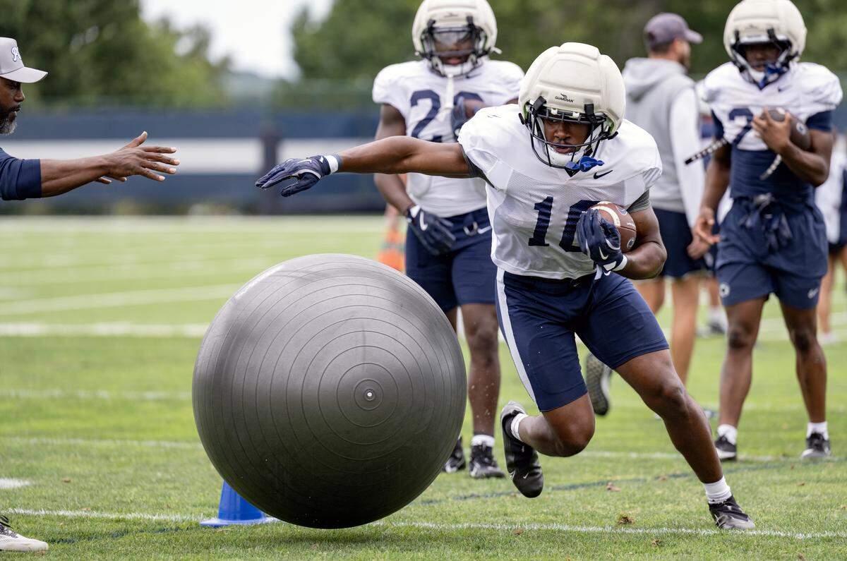 Penn State running back Nick Singleton dodges an exercise ball rolled at him by running backs coach Stan Drayton during practice on Tuesday, Aug. 19, 2025.  