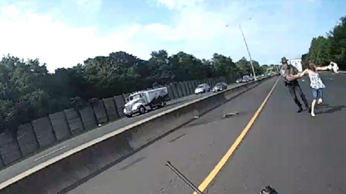 Dramatic photos released by Connecticut State Police show the moment a trooper stopped a ‘distressed’ woman from running into traffic on Interstate-95