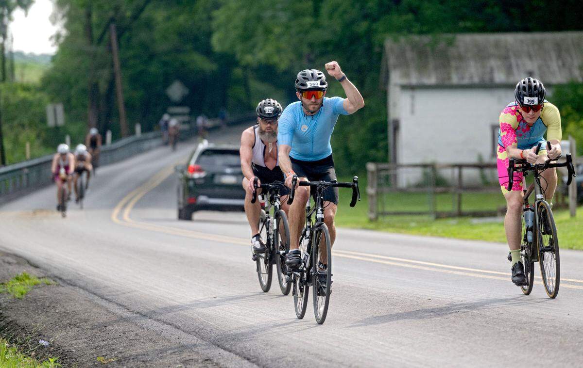 A Cyclist fist pumps as he is cheered on by community members along Jacksonville Road during the Ironman 70.3 Pennsylvania Happy Valley on Sunday, June 30, 2024.
