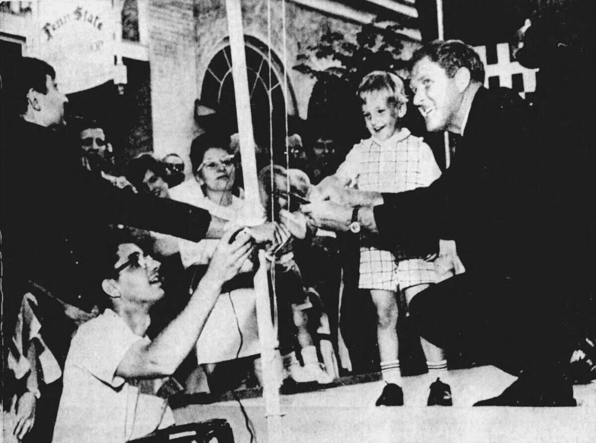 Pennsylvania Gov. Raymond P. Shafer, right, officially opens the first-ever Central Pennsylvania Festival of the Arts in State College by snipping the strings to unfurl an Arts Fest banner in July 1967. He arrived via helicopter and was joined by his grandson.