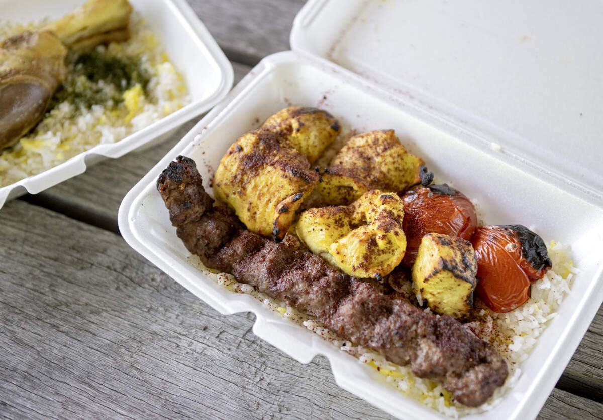 A mixed kebab plate from Fatema’s Kitchen that features skewer of ground meat and a skewer of chicken with saffron rice, butter and grilled tomato.