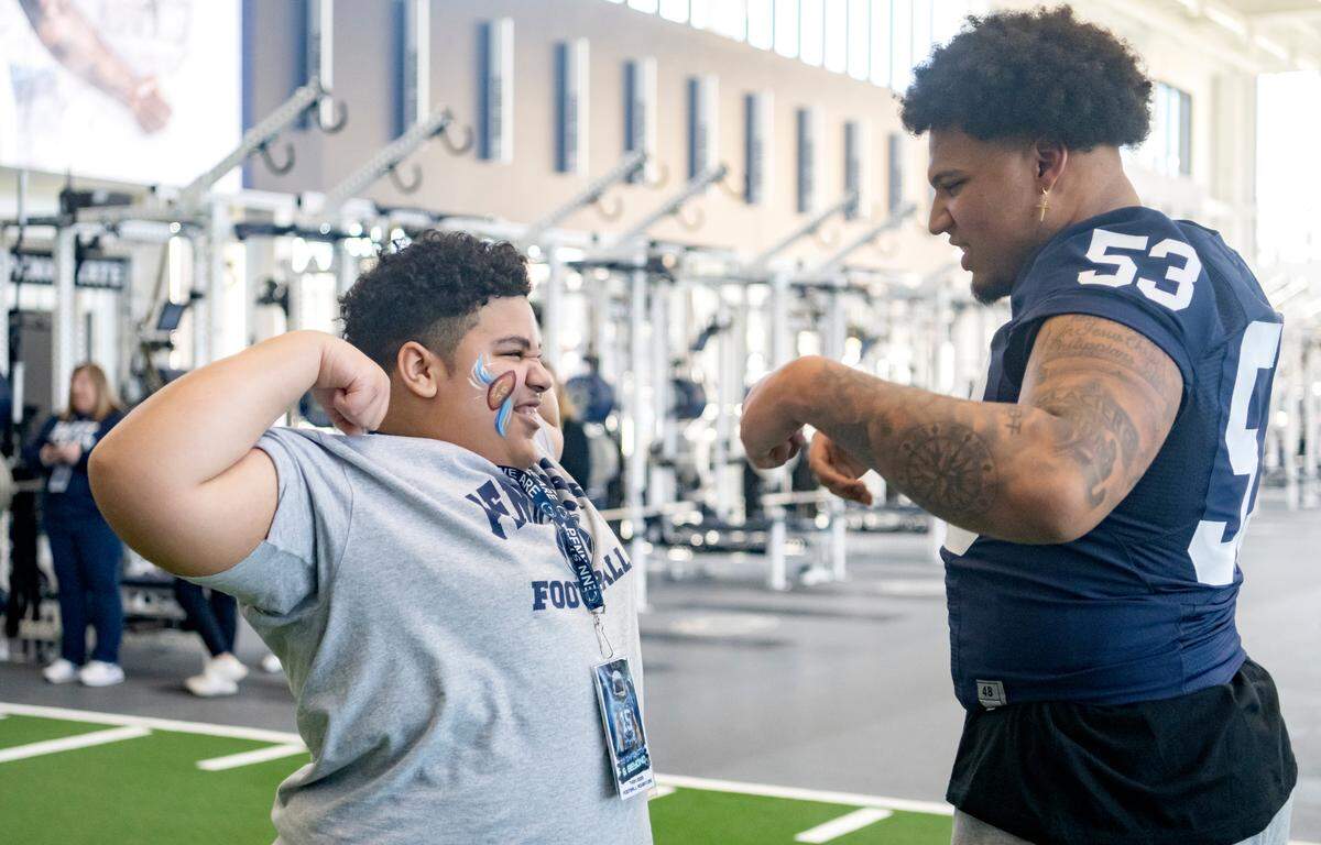 A youngster shows off his muscles to Penn State offensive lineman Nick Dawkins during the Thon Explorers program at the Lasch Building on Saturday, Feb. 18, 2023.