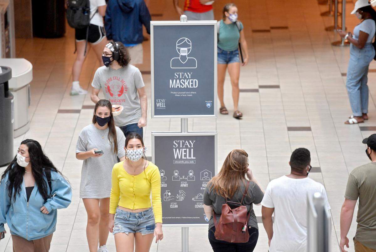 Penn State students walk through the HUB-Robenson Center around signs that remind students to wear a mask on the first day of classes for the 2020 fall semester on Aug. 24, 2020.