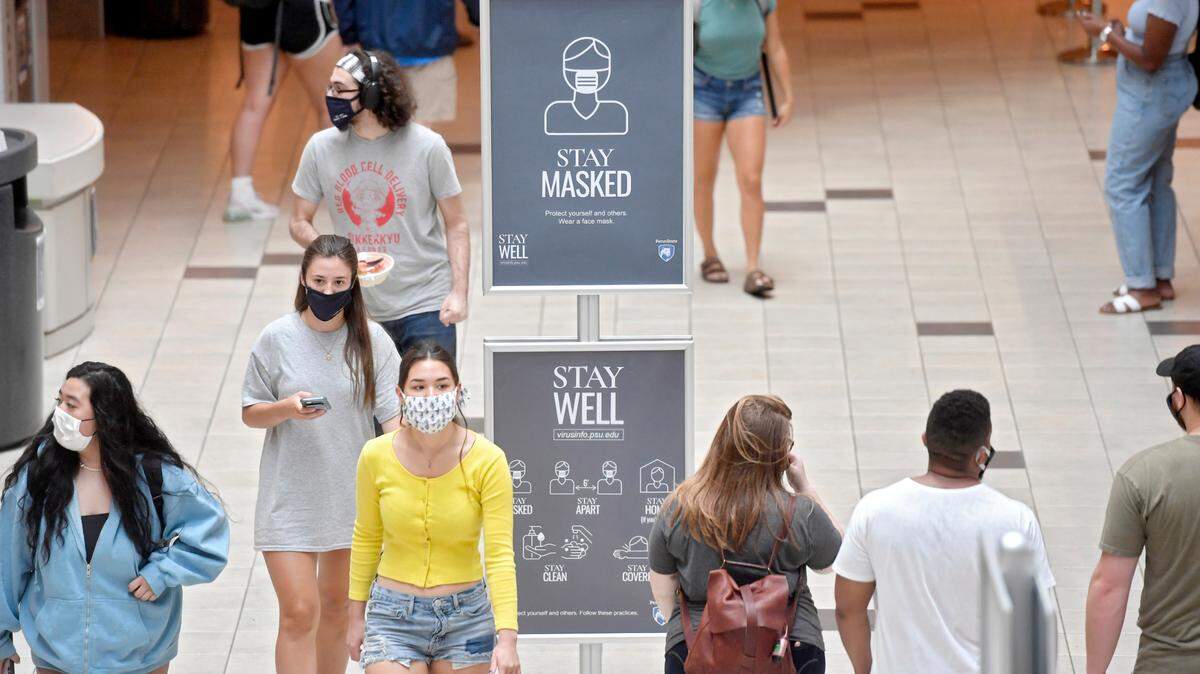 Penn State students walk through the HUB-Robenson Center around signs that remind students to wear a mask on the first day of classes for the 2020 fall semester. Penn State announced Friday that students, and all visitors, will have to continue wearing masks indoors at the start of the 2022 spring semester.