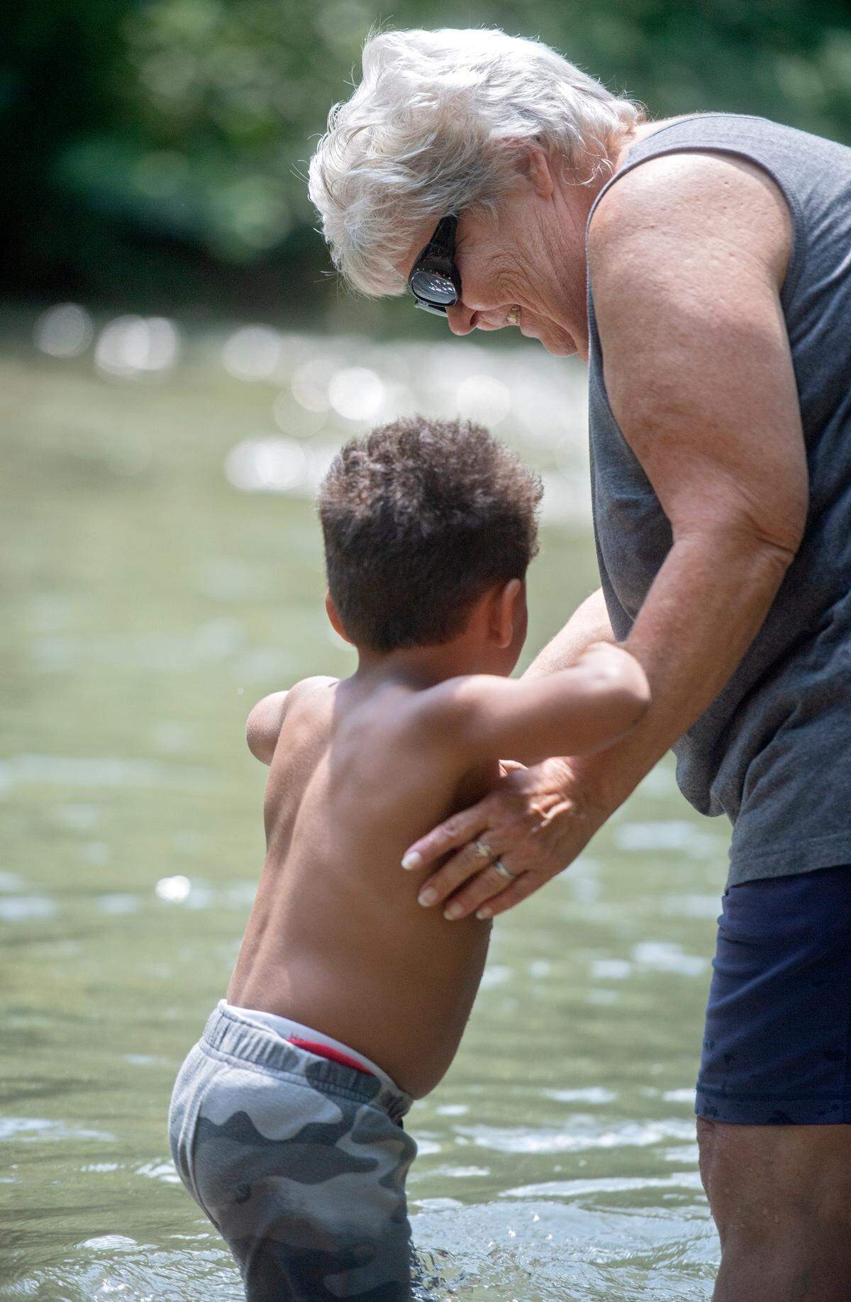 Amy Mitchell holds onto her grandson as they wade into the creek at Spring Creek Park.