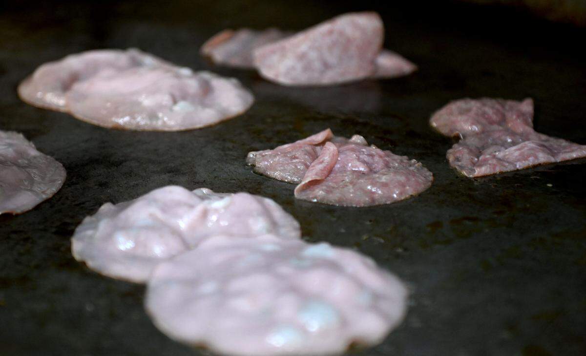 Salami and mortadella sizzle on the griddle before going on Coach Campbell’s Roman Burger at The Field.