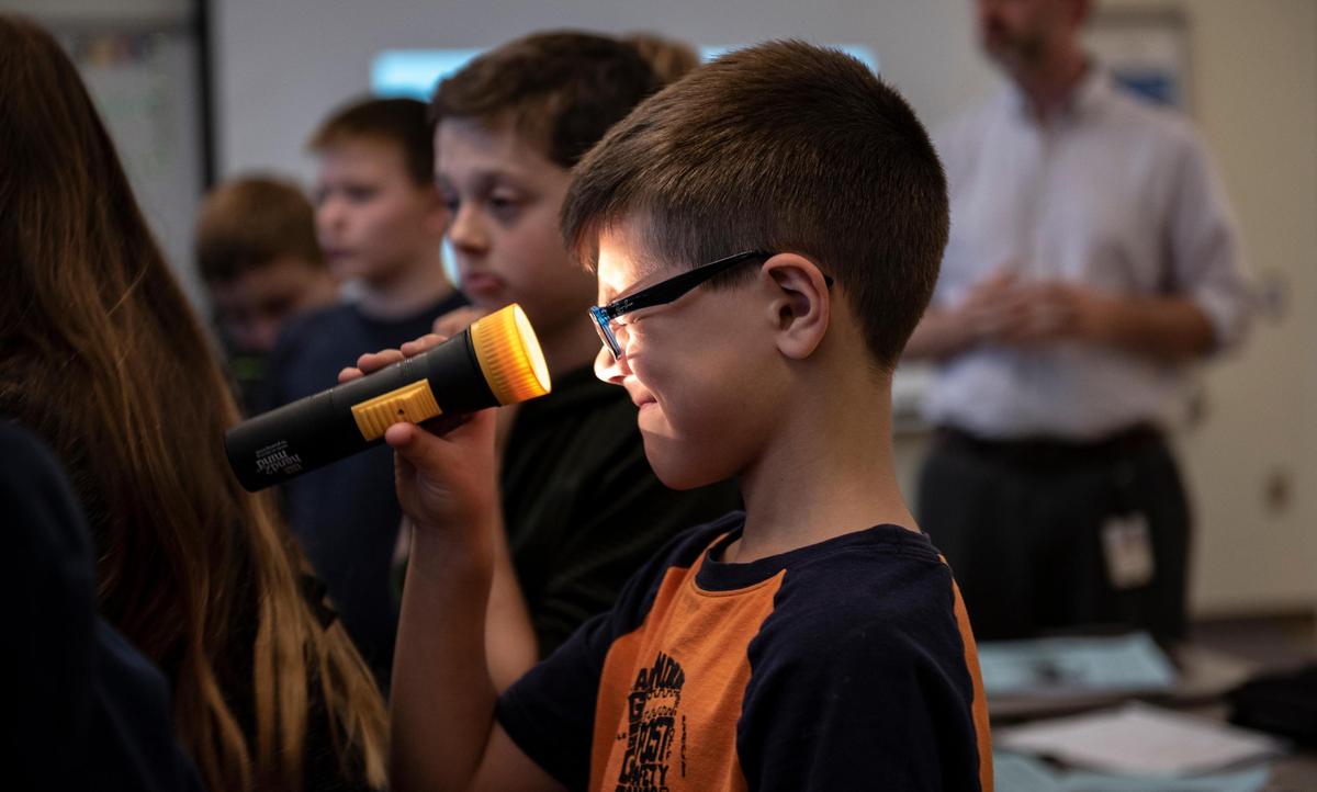 Caleb Kraft, a 5th grade student, shines the flashlight on his eyes in the STEM class on Oct. 17, 2018, at Ferguson Township Elementary School in State College, Pa. (Photo/Baidi Wang)