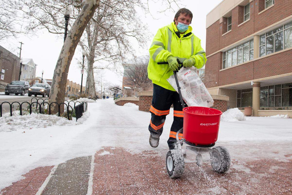 Chris Secrest, a worker for the Borough of State College, salts in front of the State College Municipal Building on Friday after a storm.